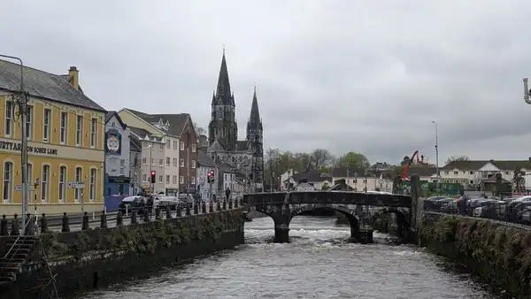 A stone bridge over an old-town river beneath colourful houses and church spires on a grey day